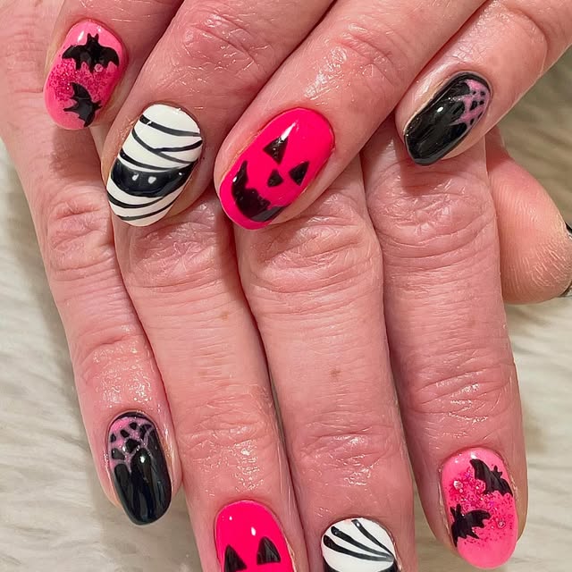 Neon pink Halloween nails with bats and pumpkins